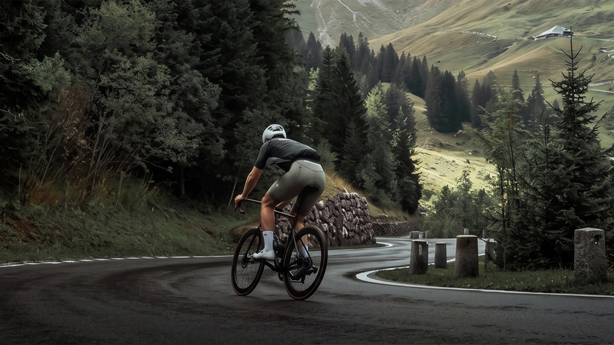 All-weather endurance cycling landscape with rider on mountain road